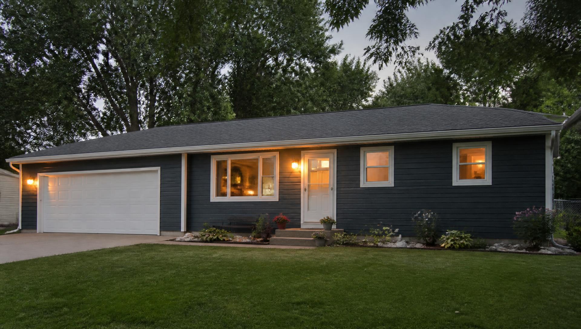 Iowa ranch home at dusk with newly installed dark gray siding and warm porch lighting
